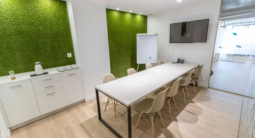 Sala de reuniones mediana con pared vegetal y pantalla